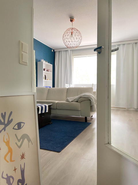 Näkymä olohuoneeseen, jossa sininen matto ja valkoinen sohva. Kuva Heidi Lehto