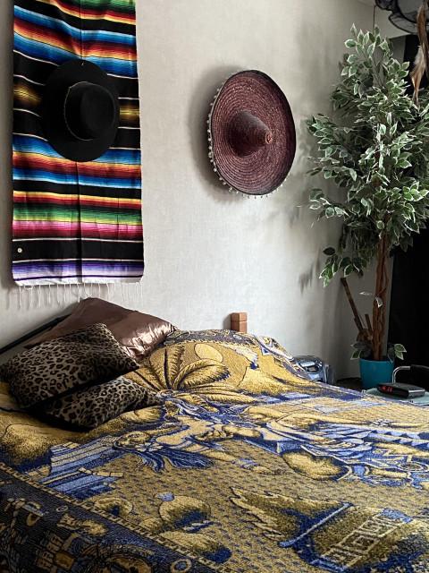 Makuuhuoneen sängynpäädyssä on seinävaate ja hattu. Kuva Heidi Lehto